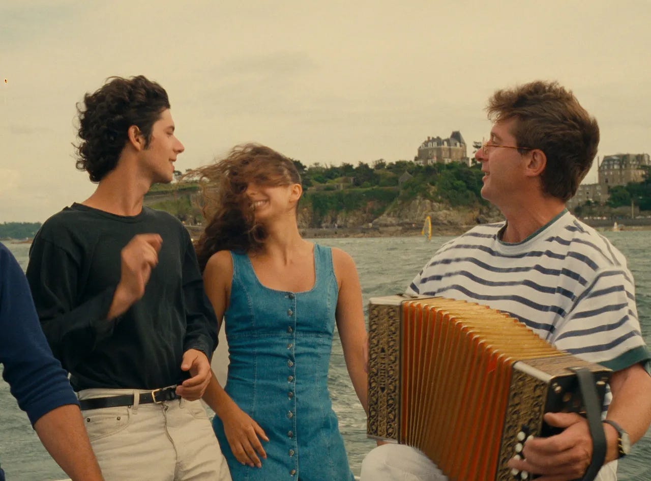 A man and woman enjoy the music of an accordion player on a boat.