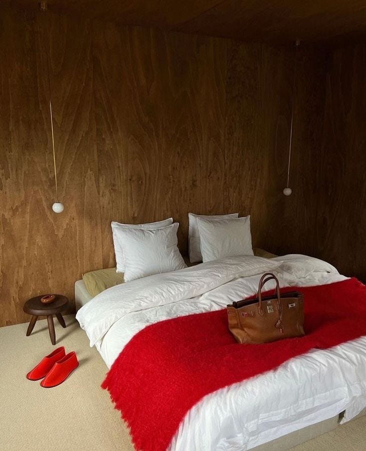 This may contain: a red and white bed in a room with wooden walls