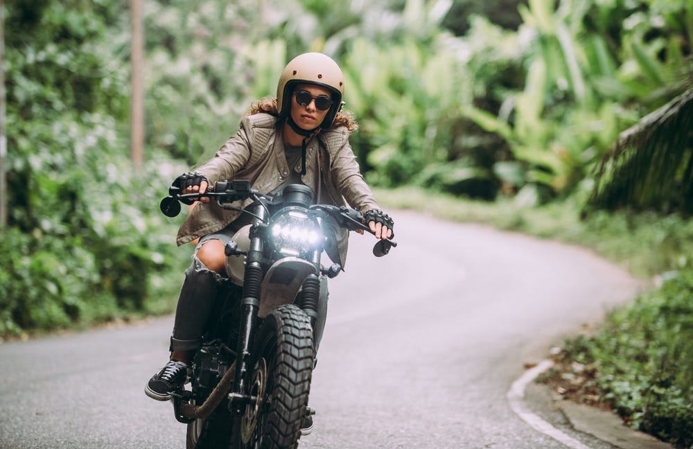 Young woman wearing helmet and dark glasses riding a motorcycle