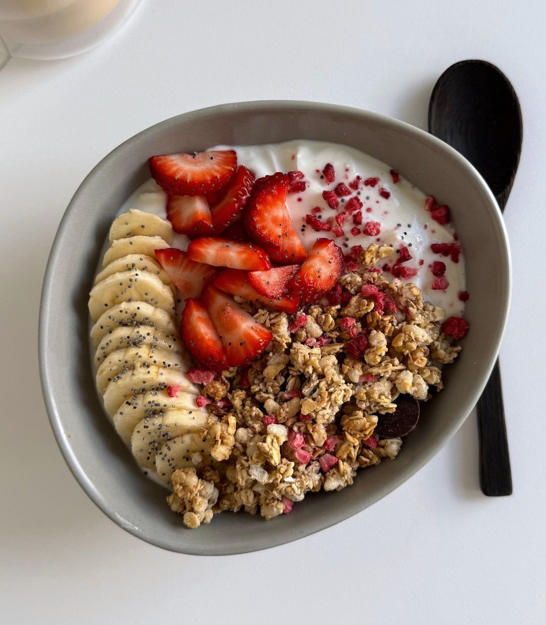 Overhead shot of a protein-packed yogurt bowl with vanilla-flavored yogurt, fresh berries, granola clusters, and vibrant dried raspberries.