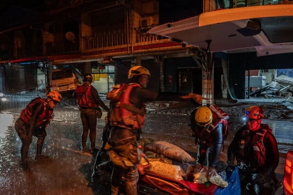 Rescuers wearing helmets and life vests transport a resident on a stretcher.