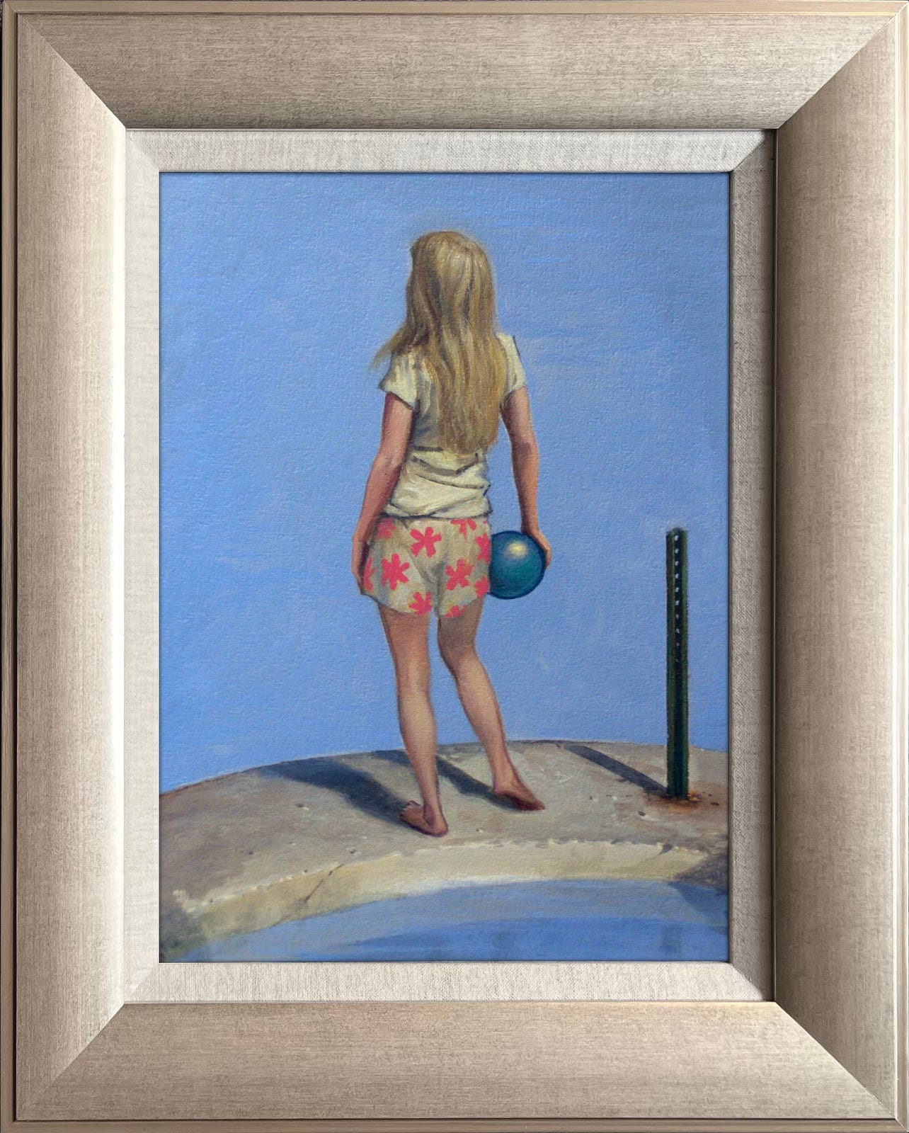 Figure study for SEAWALL. Custom framed original art in silver wood moulding with linen liner. Features a girl in white shirt and shorts patterned with 5-pointed pink blossoms. She holds a blue rubber ball at her hip. Next to her, the broken base of a street sign juts out of the concrete.
