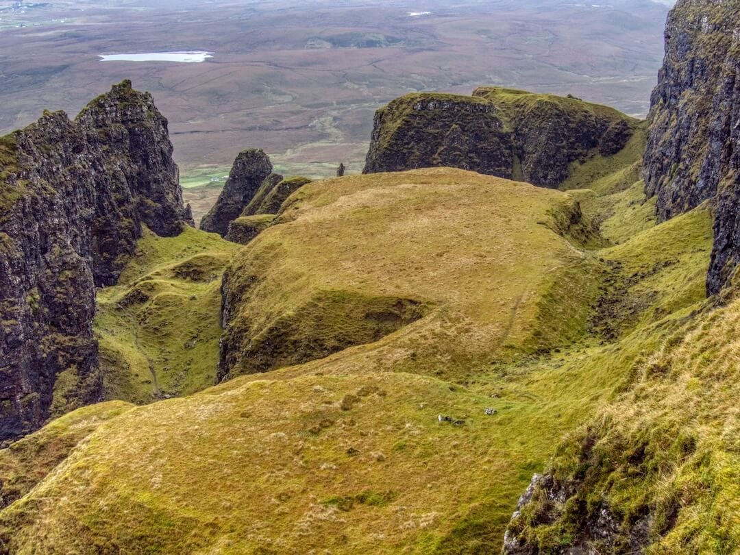 A flat, grassy area sandwiched between two sets of cliffs