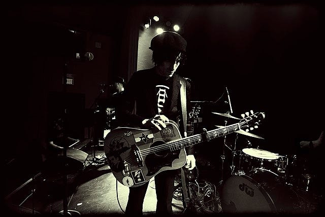 Jesse Malin in concert holding a guitar