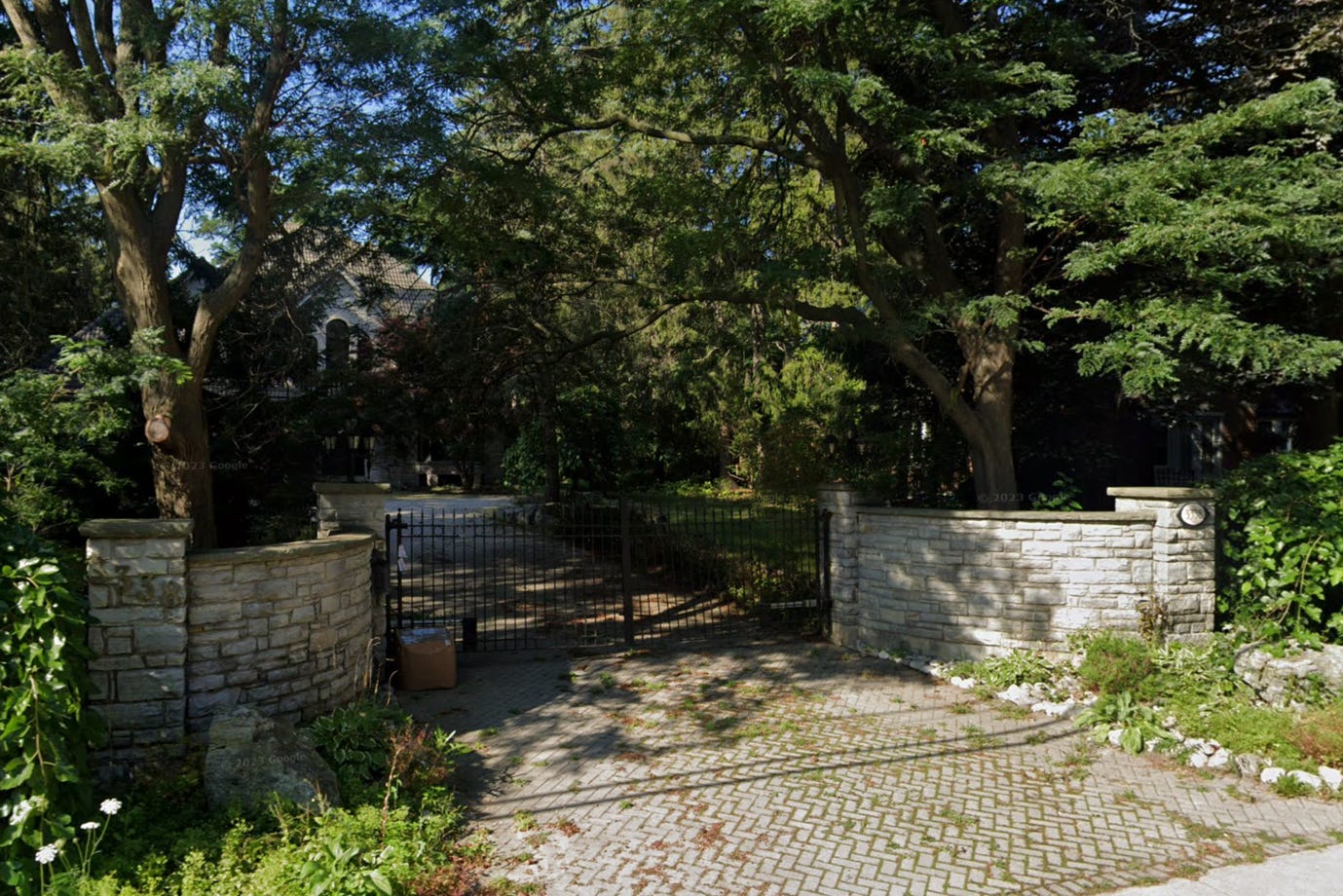 A gated driveway with trees and grass

AI-generated content may be incorrect.