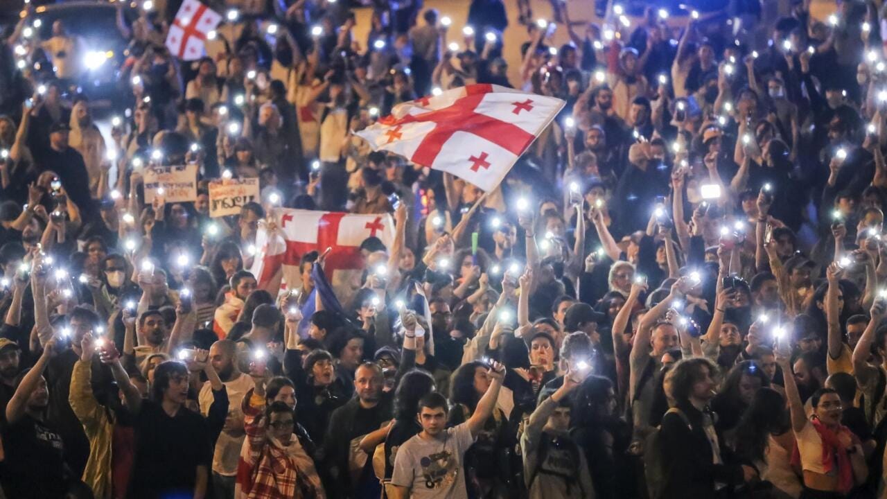Huge crowd of protestors in Georgia hold up their phone lights and Georgian flags Huge crowd of protestors in Georgia hold up their phone lights and Georgian flags