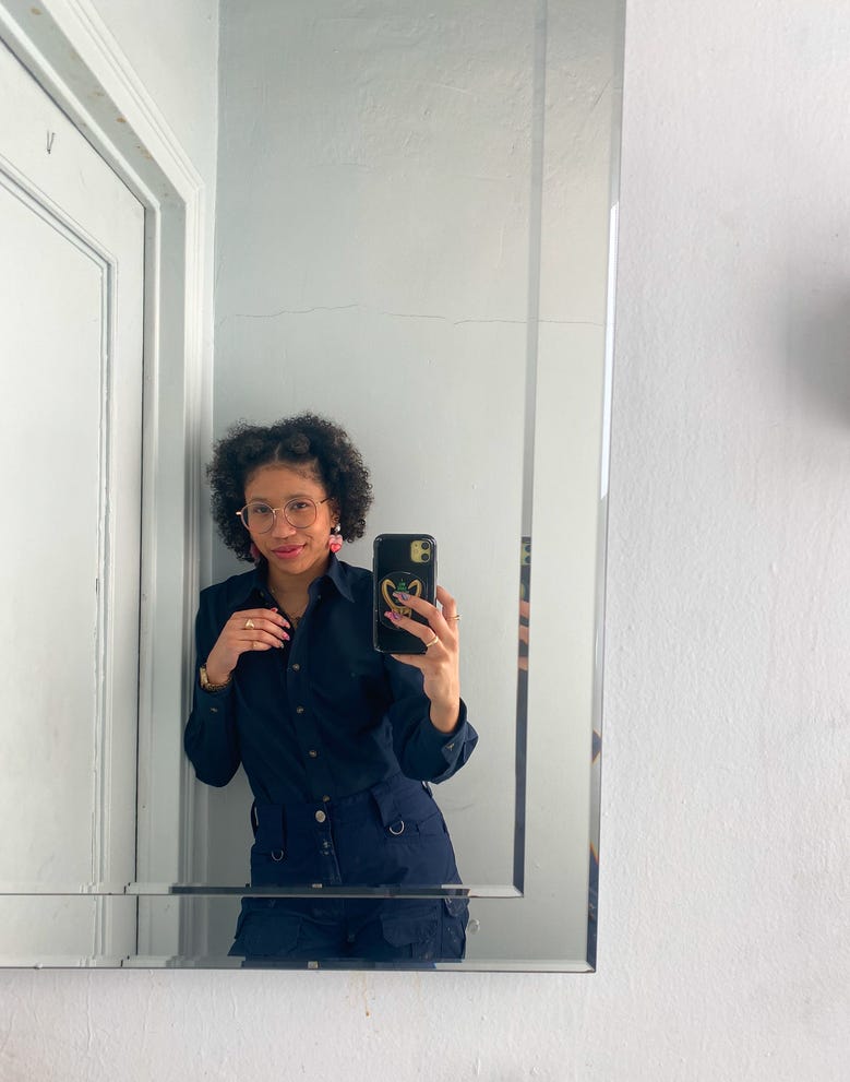 Kiana taking a mirror selfie and wearing her porter uniform