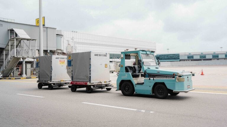 A turquoise driverless tractor deployed airside at Changi Airport.