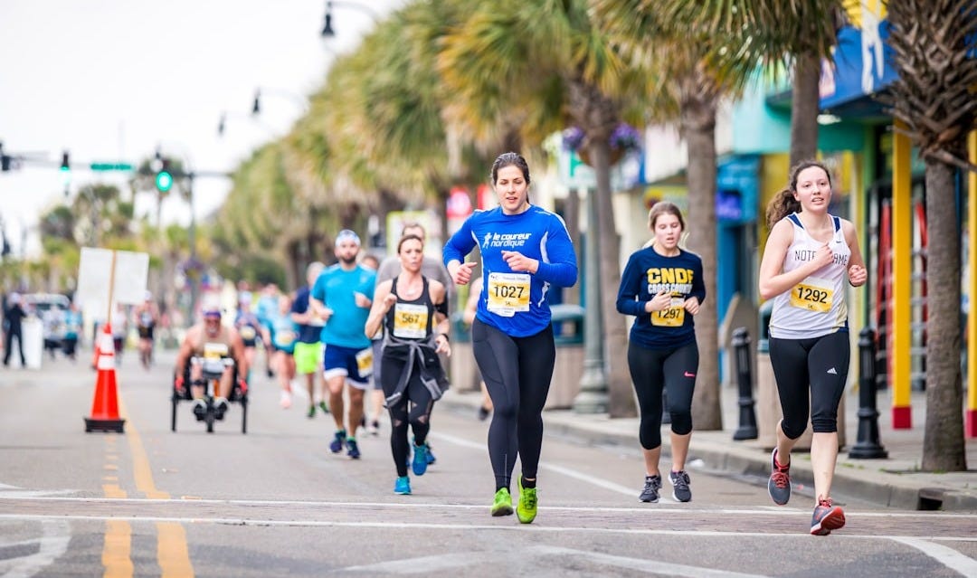 group of people running on the road during daytime