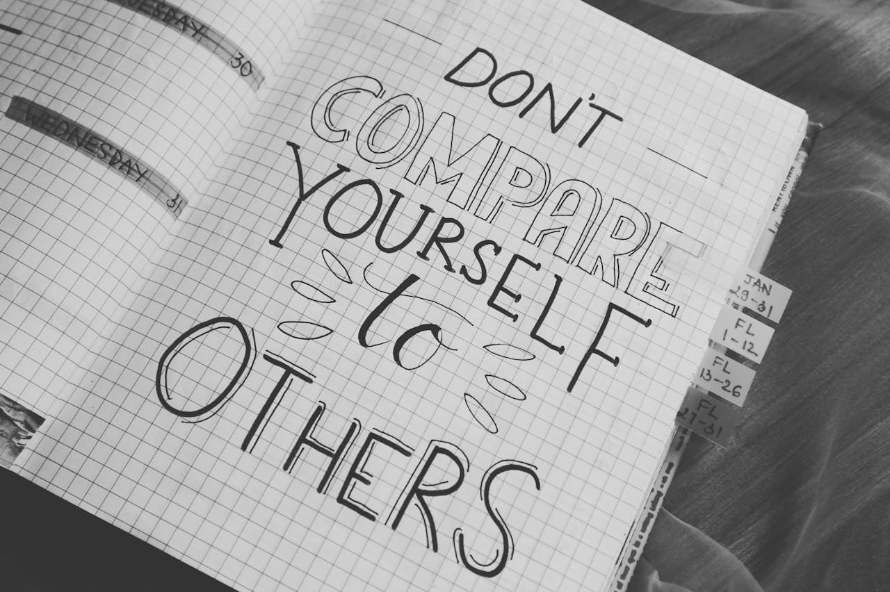 'Don't Compare Yourself to Others" doodled on an open notebook page