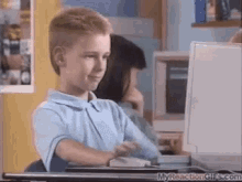 a young boy is sitting at a desk in front of a computer screen which says myreactiongifs.com on the bottom a young boy is sitting at a desk in front of a computer screen which says myreactiongifs.com on the bottom