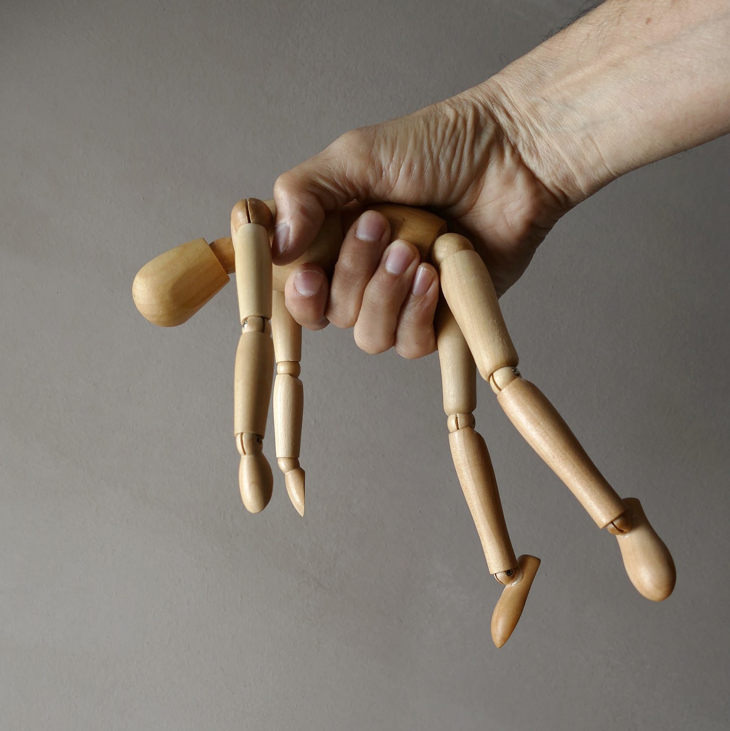 Hand roughly holding jointed wooden doll Hand roughly holding jointed wooden doll