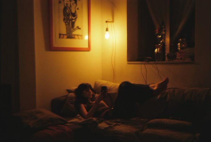 This may contain: a person sitting on a couch reading a book in front of a light that is turned on