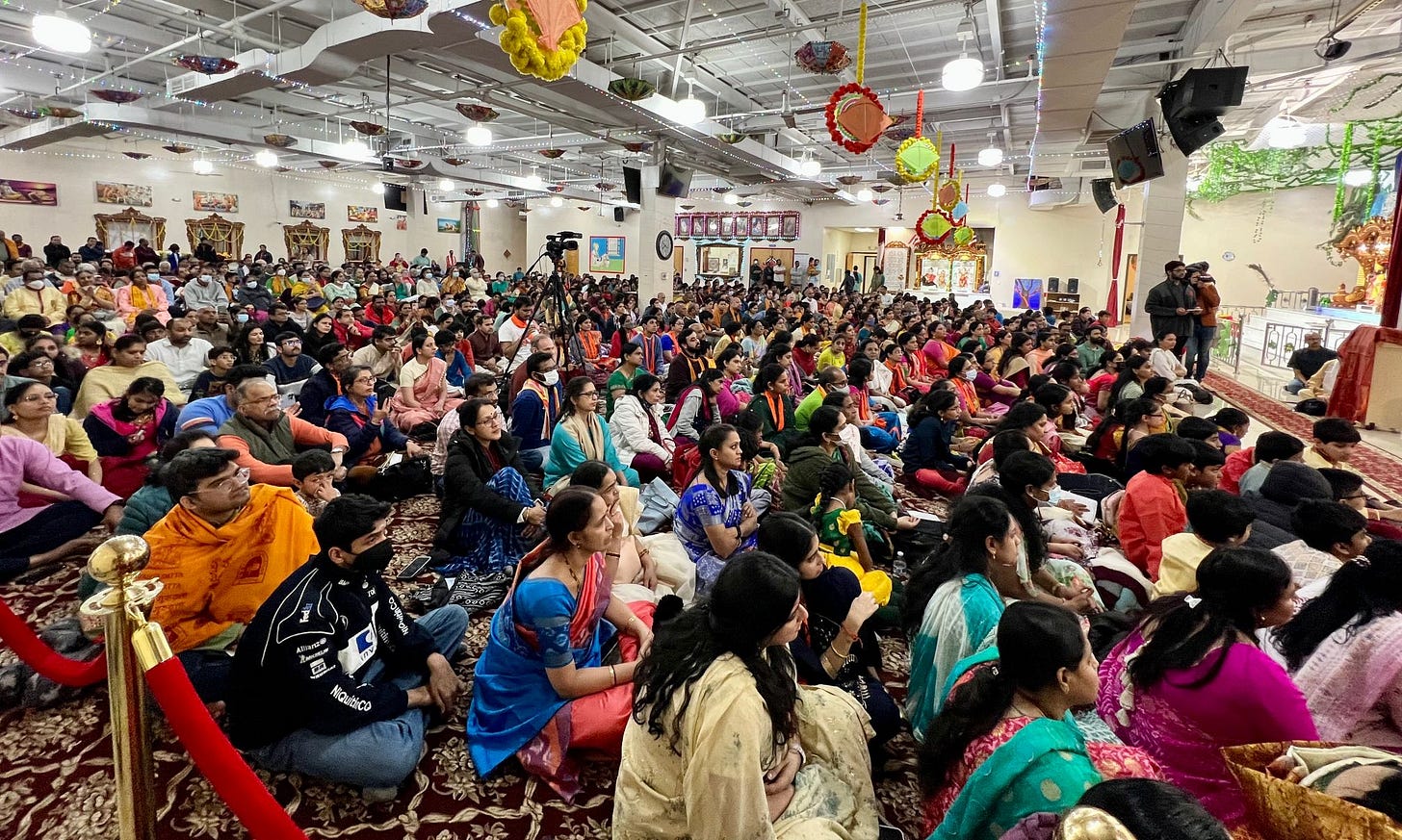 Devotees sit in the temple main room with rapt attention Devotees sit in the temple main room with rapt attention