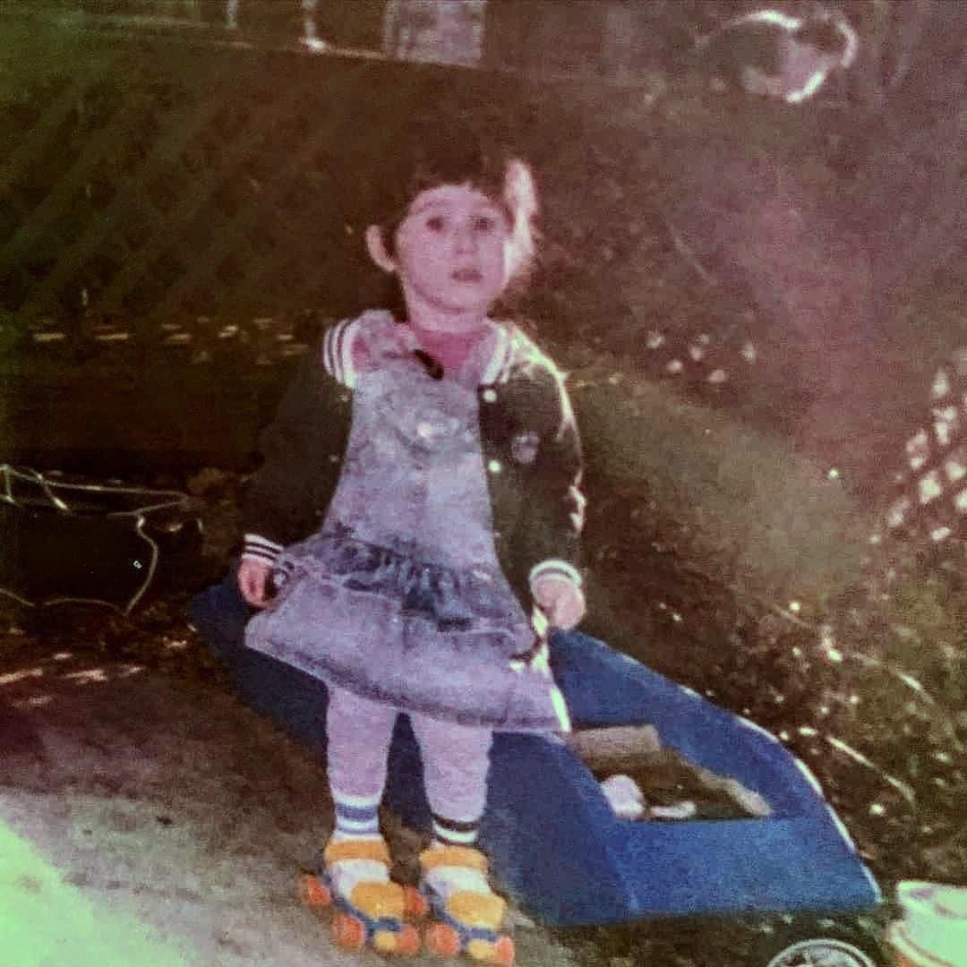 Young Lyric, pale with dark hair, bangs and a braid, wearing a denim outfit and orange and blue Fischer Price skates.