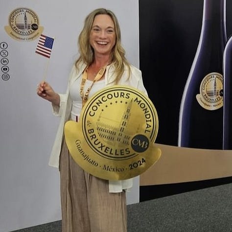 Kristy posing with Concours Mondial de Bruxelles signage across three years of judging: the 2026 Yerevan, Armenia session with the Vine & Wine Foundation of Armenia logo, the 2024 Guanajuato, Mexico session holding a U.S. flag, and the 2025 China session holding her certificate of participation amid rows of judging tables