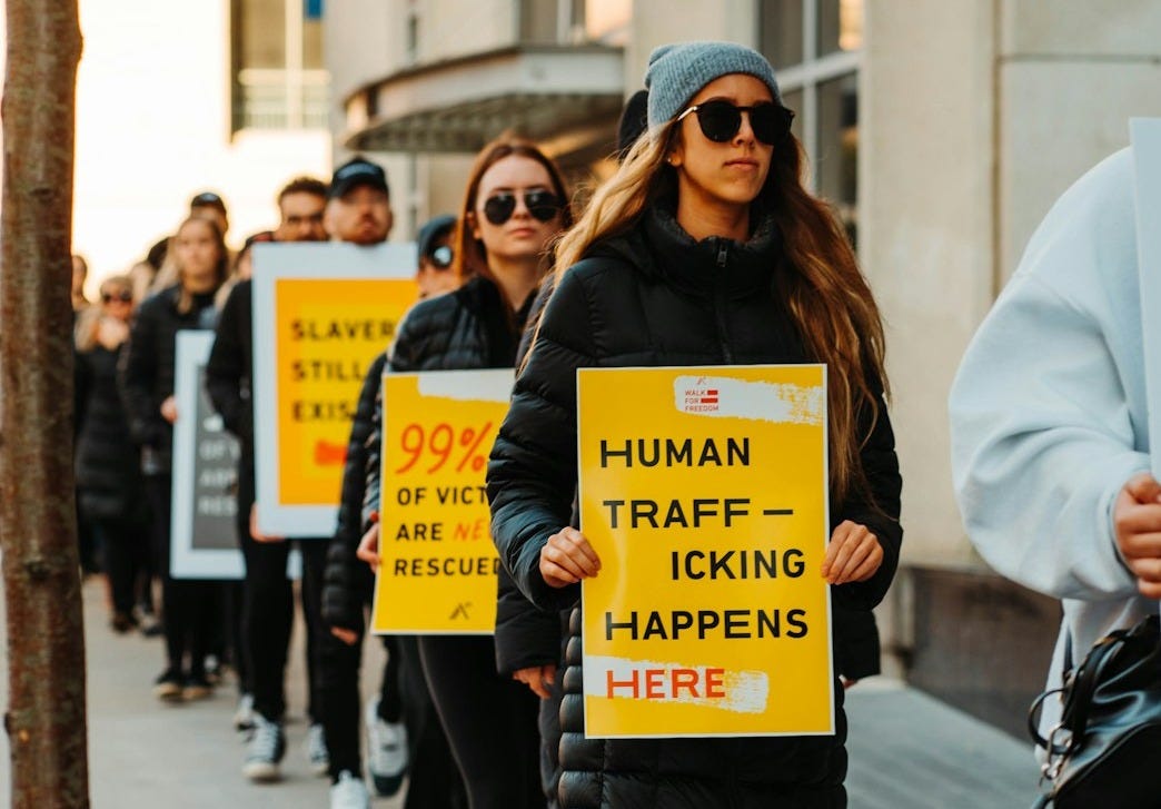 woman in white coat holding yellow and black signage