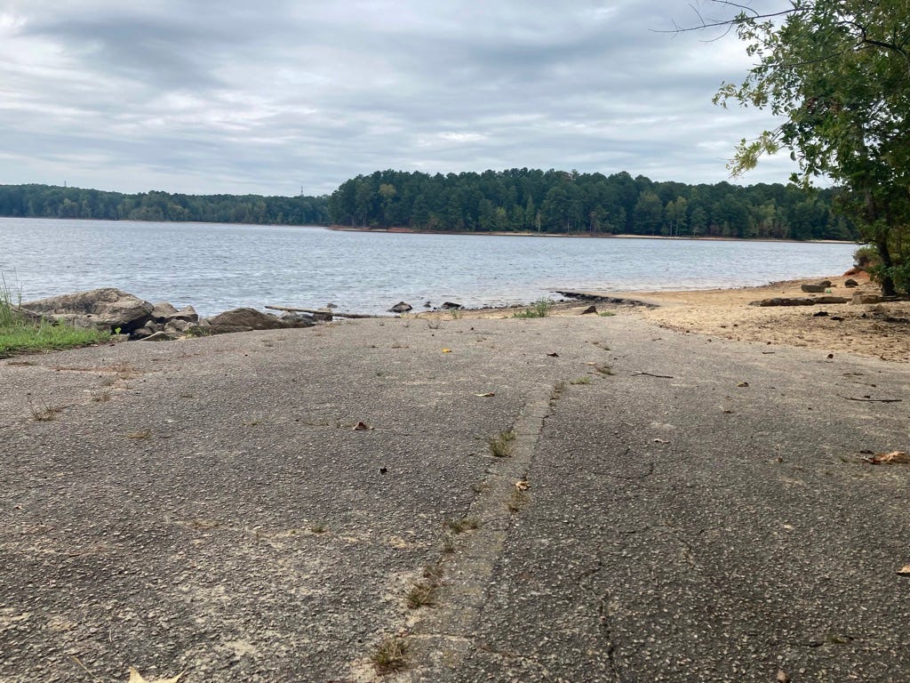 asphalt road with faded yellow line breaking up at the lakeshore