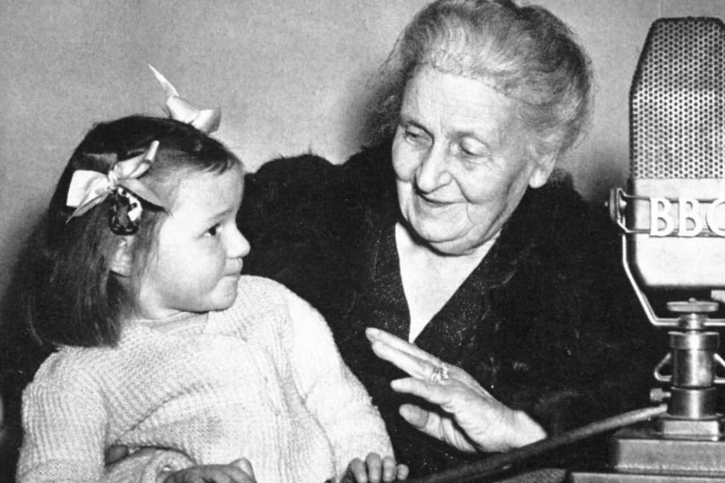 Dr. Maria Montessori with a young child at a BBC microphone — what is Montessori and the child-centered approach