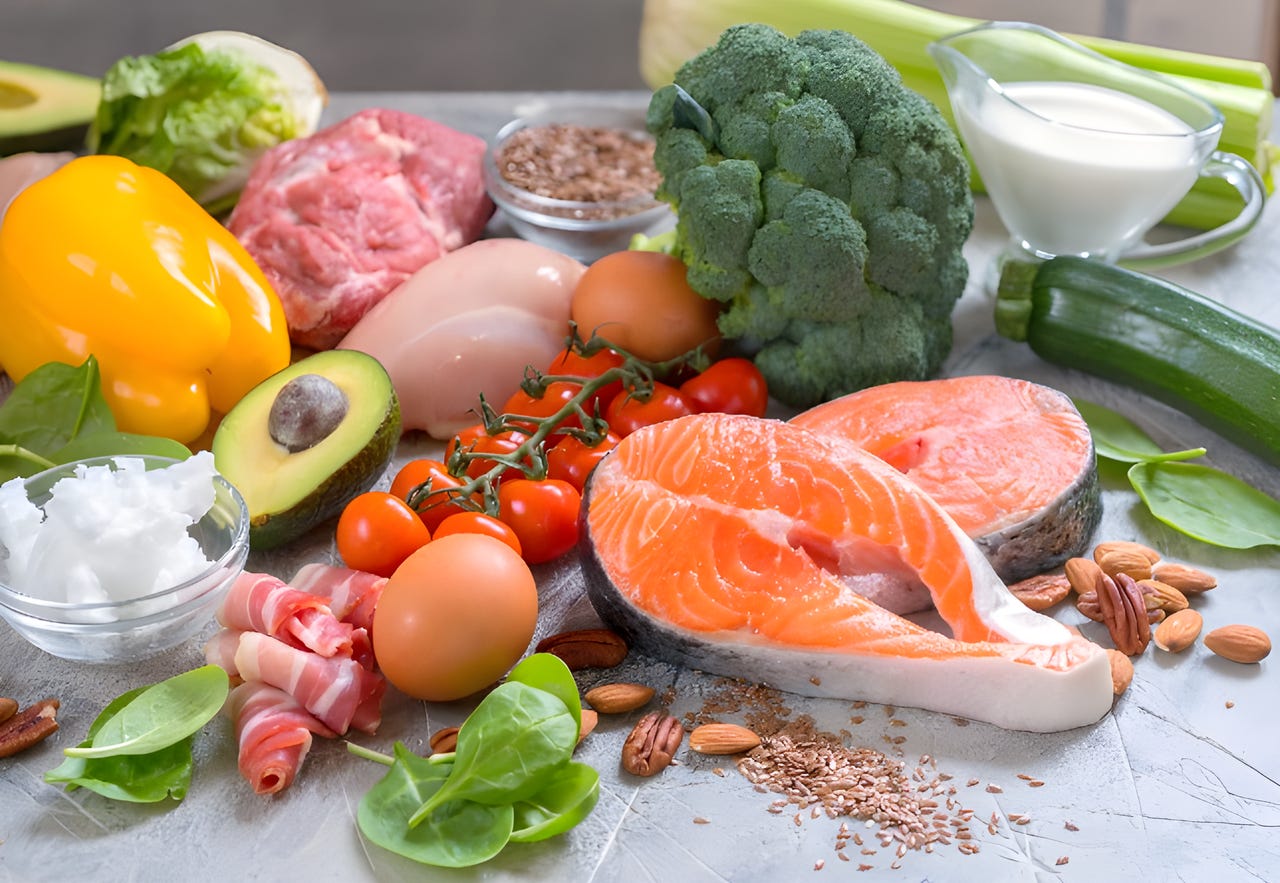 Array of healthy foods like salmon, broccoli, spinach, avocado, and zucchini.