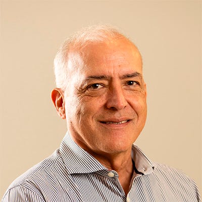 Homem branco calvo com cabelo branco. Usa camisa social listrada e sorri para a foto Homem branco calvo com cabelo branco. Usa camisa social listrada e sorri para a foto