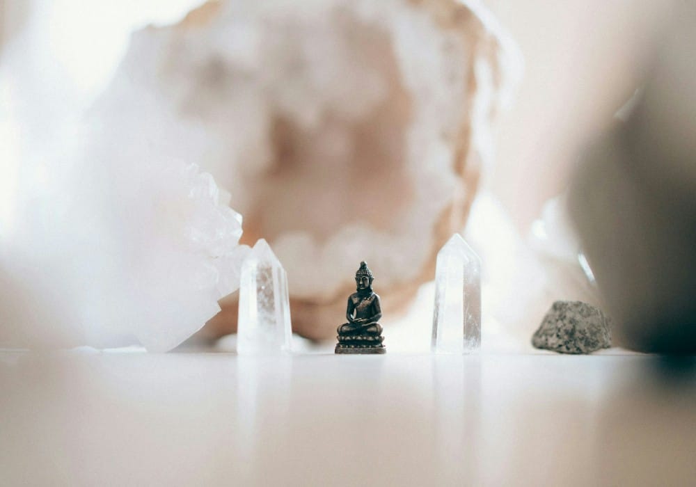Pink, translucent and black crystals surrounding a tiny Buddha statue