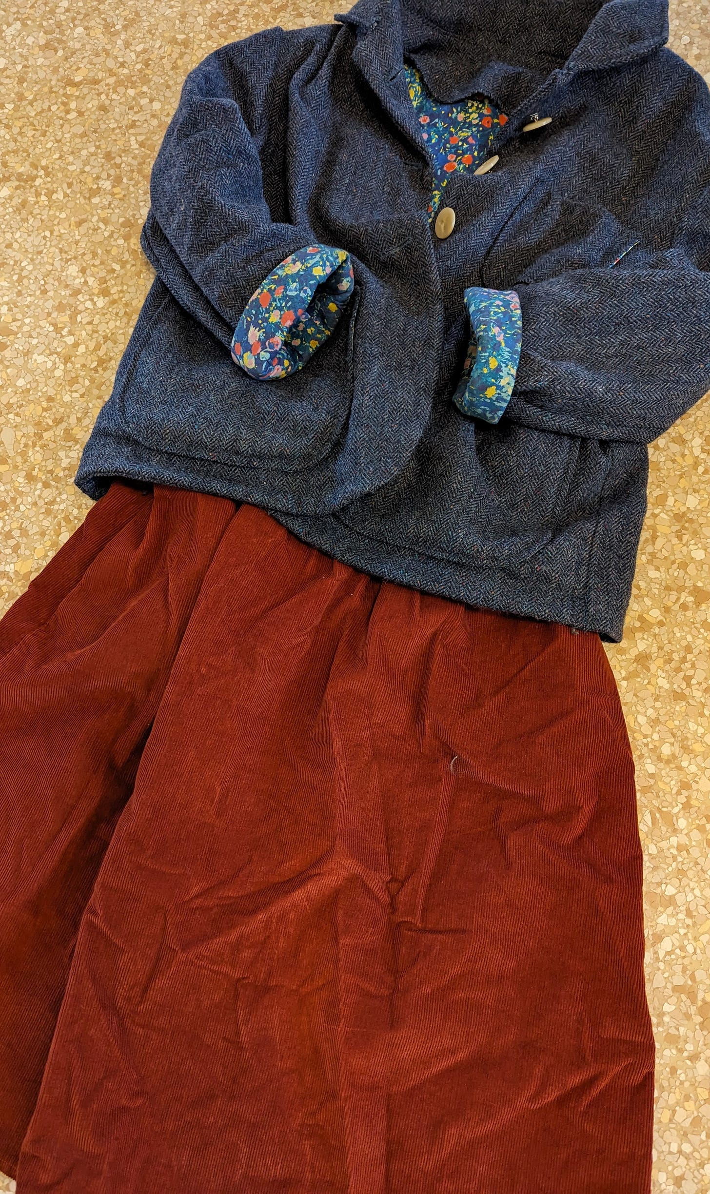 Blue tweed jacket with blue floral lining and ivory buttons, posed with a rust-orange corduory skirt