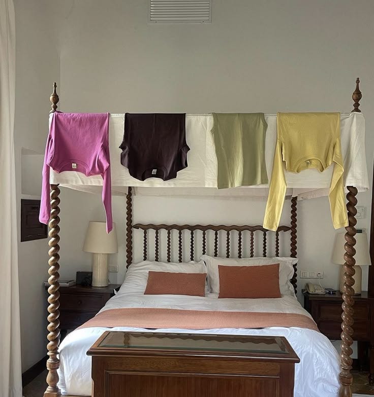 This may contain: a bed with four hanging clothes on it