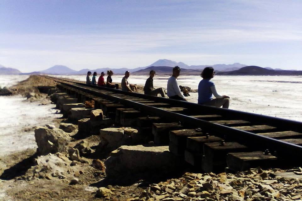 Ocho turistas posan sobre vía de tren en un salar en Bolivia.