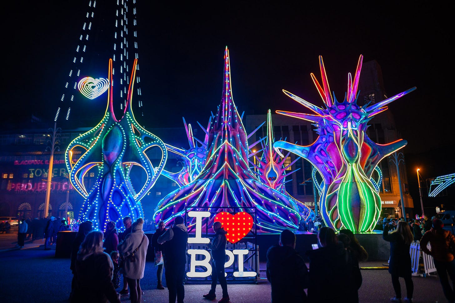 A sign saying I heart BPL glows in front of large monstrous colourfully lit illuminations.