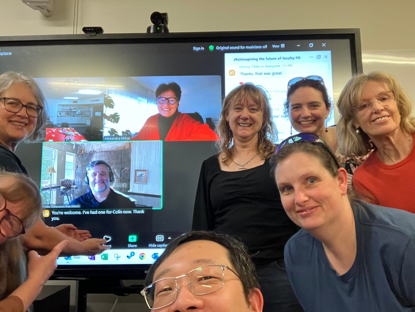 selfie of the Canberra watch party for ‘Reimagining the future of Faculty professional development’ - a group of Third Space workers in a physical space join with the presenters who are in Zoom: Alexandra Mihai and Colin Simpson, as part of the Slowposium. Everyone is smiling.