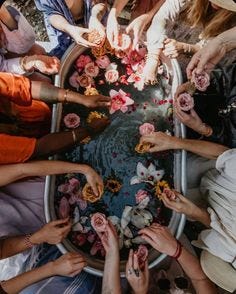 This may contain: a group of people standing around each other with their hands together and flowers on the table
