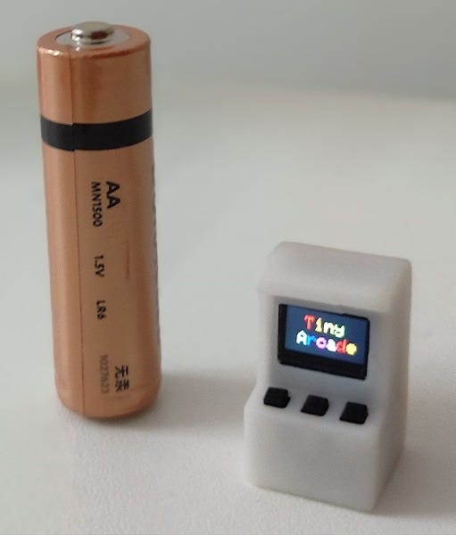 split image of smallest arcade machine next to a battery and on a laptop
