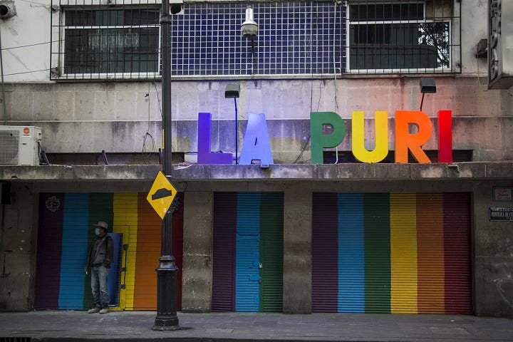 A fabulous queer poses in front of the decorations at La Purisima. The rainbow colored doors of La Puri by day.