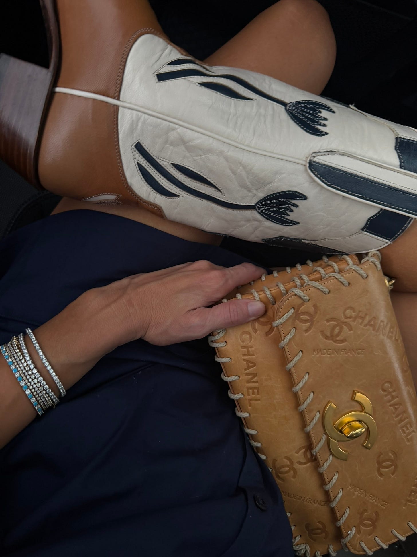 detail shot of cowboy boots, chanel bag, rodeo look