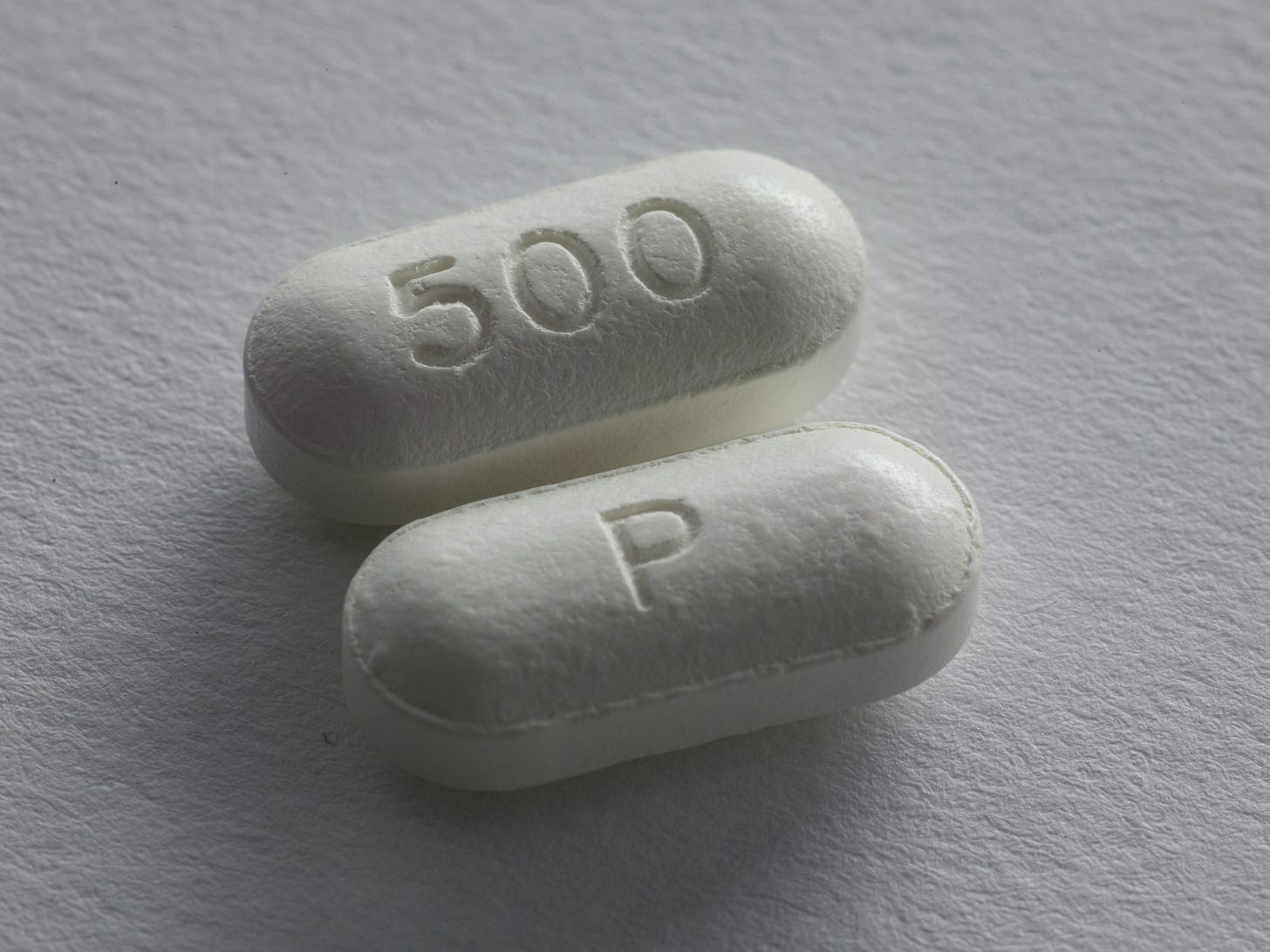 Dvě pilulky. Jedna s nápisem 500 a druhá s písmenem P Dvě pilulky. Jedna s nápisem 500 a druhá s písmenem P