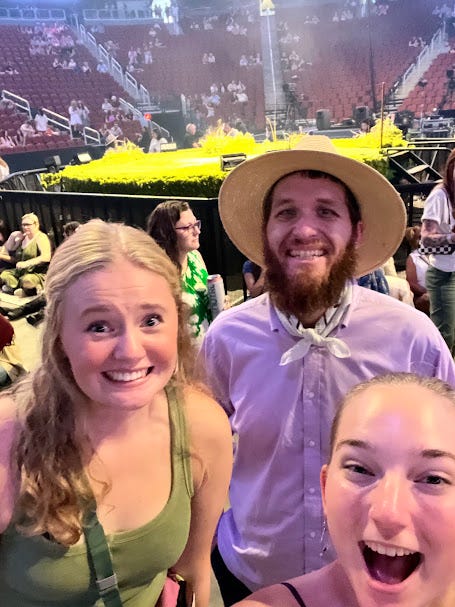 Three people posing together in front of a music stage.