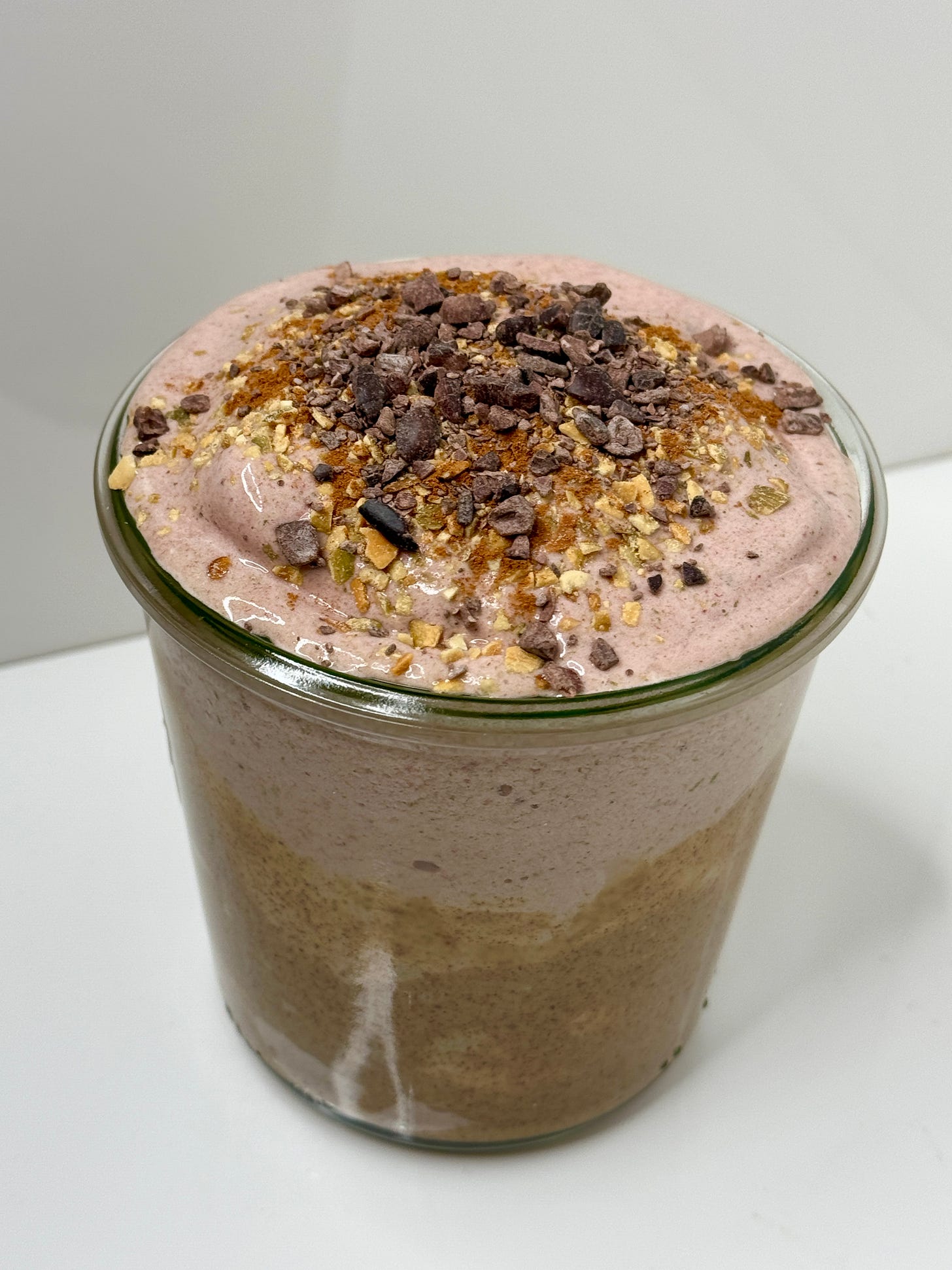 Cacao almond butter smoothie topped with cacao nibs, pumpkin seeds, hemp seeds, and cinnamon