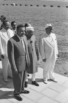 Men in suits stand by the coast. Men in suits stand by the coast.