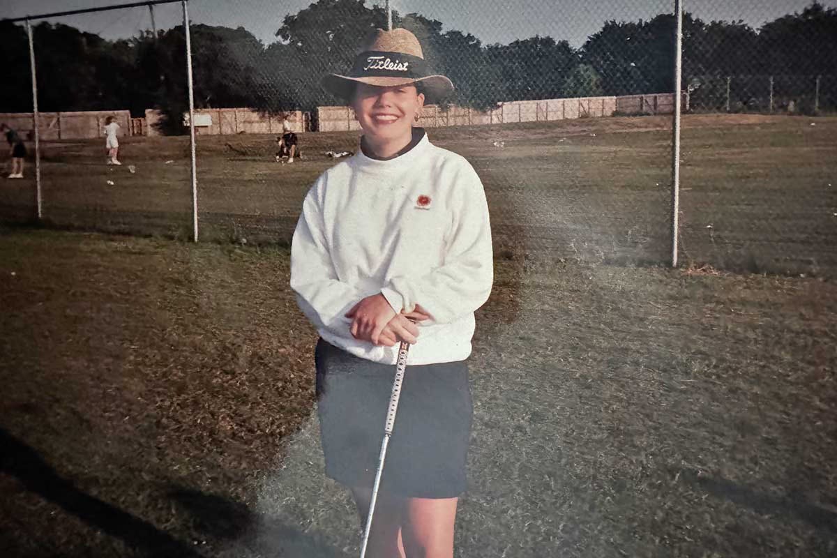 Kristi Koeter in high school posing with a club at the golf range