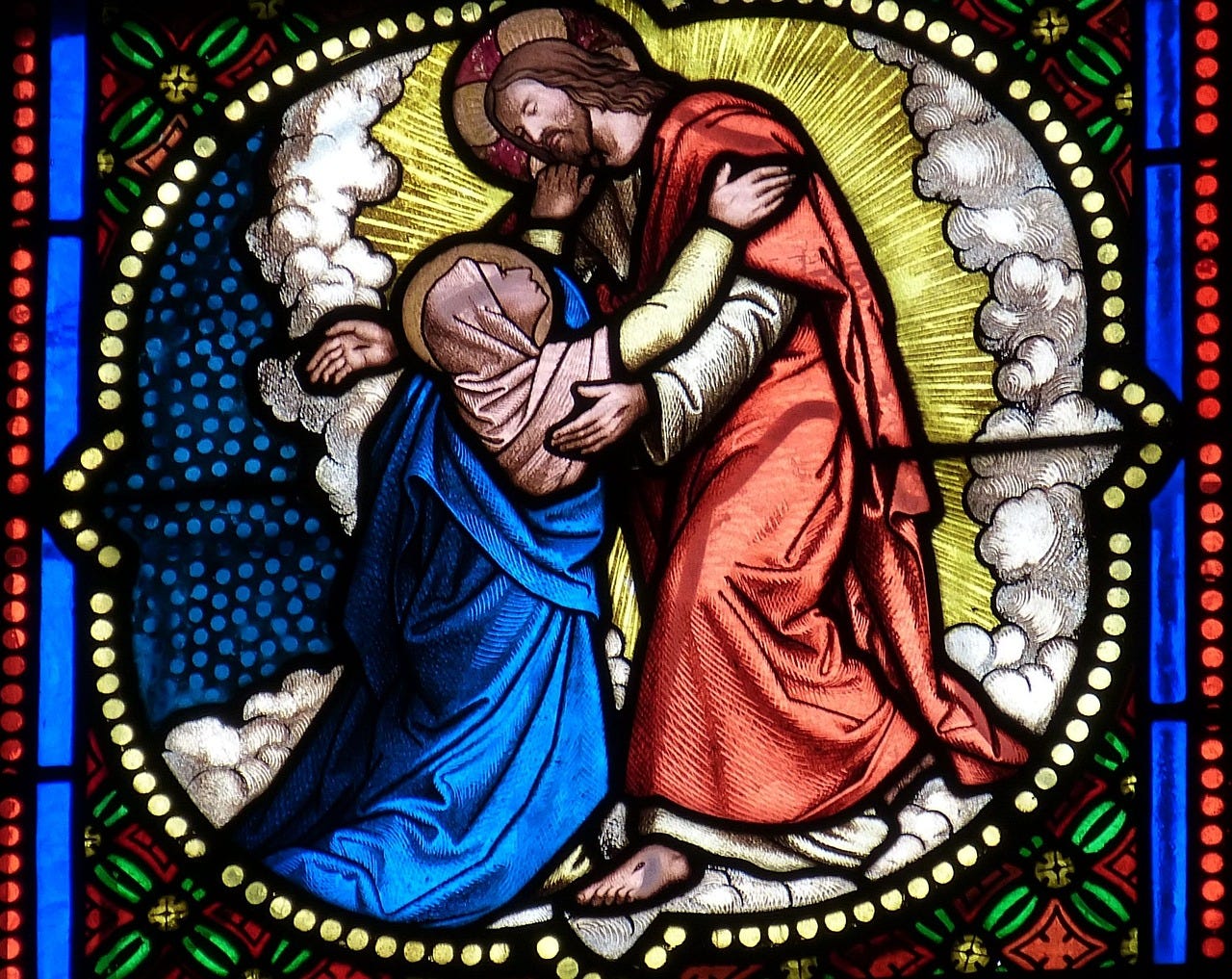 Photo of a stained glass window featuring a post-resurrected Jesus embracing Mary Magdalene, who has fallen on her knees in recognition