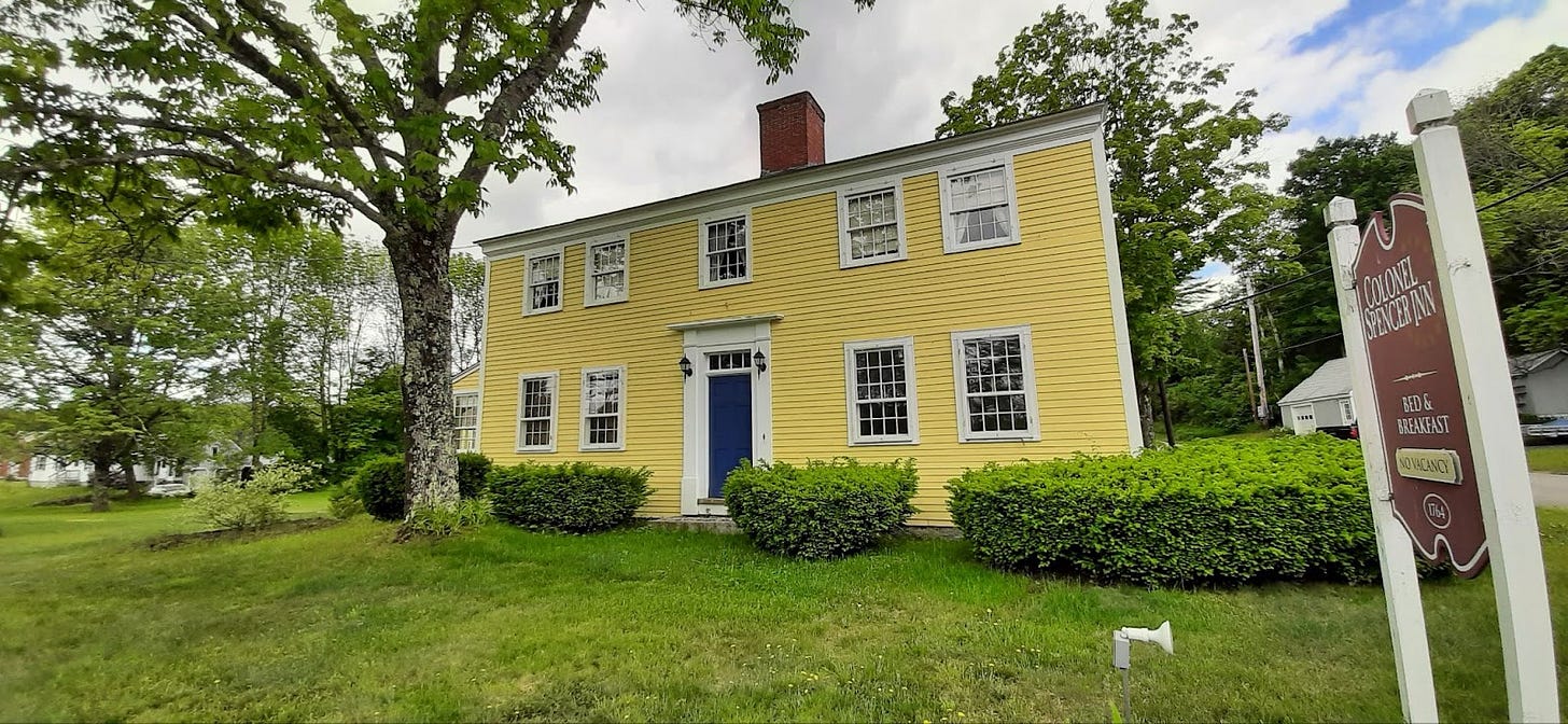 A rectangular yellow home with five windows on the second floor and a chimmney in the middle of the roof.