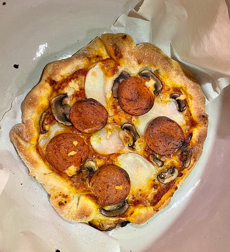 pizza dough on a counter, baked pizza sitting in a dutch oven, sliced pizza in a grey round bowl