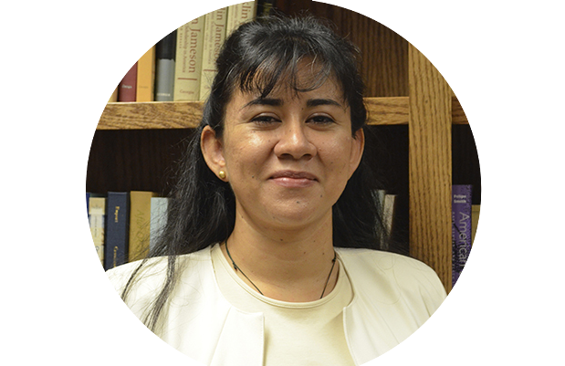 a photo of a woman with brown skin looking at the camera. She has long black hair and bangs. Her shirt is white.