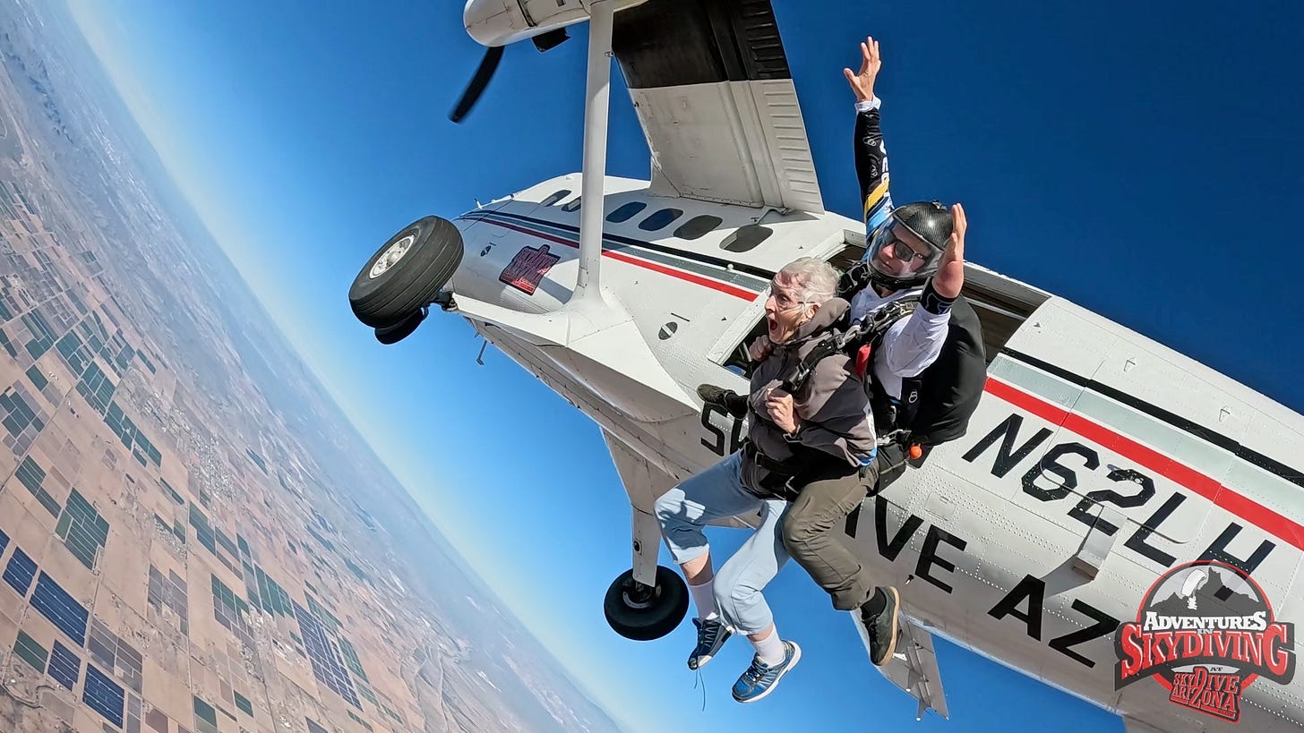 Donna Blevins tandem skydiving, captured at the moment she exits a small aircraft high above the Arizona desert on December 7, 2025, arms tucked in and mouth open in exhilaration as her instructor, Colby Groom, raises his arms, with farmland visible far below and clear blue sky overhead. Donna Blevins tandem skydiving, captured at the moment she exits a small aircraft high above the Arizona desert on December 7, 2025, arms tucked in and mouth open in exhilaration as her instructor, Colby Groom, raises his arms, with farmland visible far below and clear blue sky overhead.