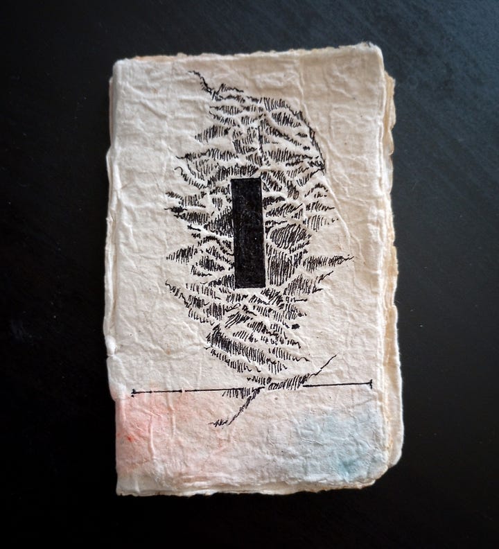 Two photos, one of the front cover of the book, which has a black "slot" drawn on the front in ink, surrounded by wavy lines. The second photo is of the interior of the book's blank pages, with some pale pink ink stains in it.