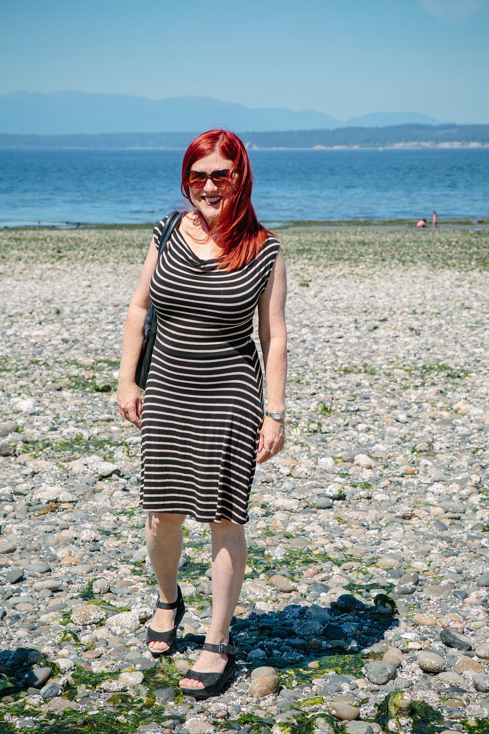 A red-haired woman in a black and gold striped dress on the beach. A red-haired woman in a black and gold striped dress on the beach.