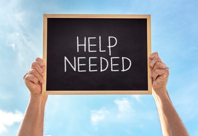 Help needed sign held up by man against blue sky background Help needed sign held up by man against blue sky background