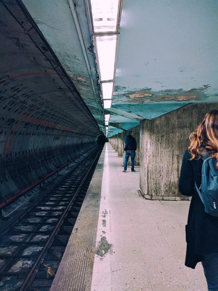 two people waiting at a train stop two people waiting at a train stop