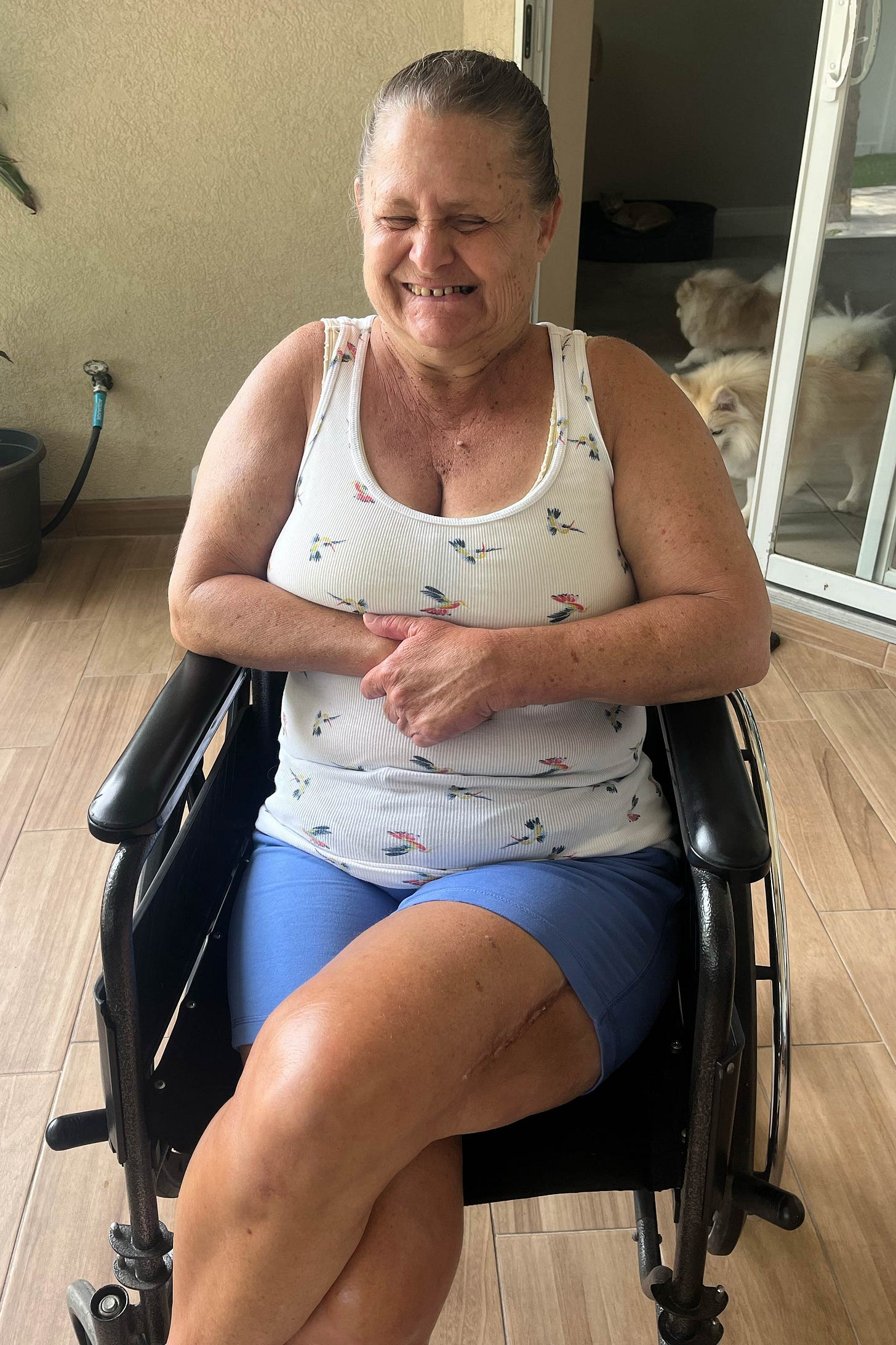 A photo of a woman smiling and sitting in a wheelchair indoors. A photo of a woman smiling and sitting in a wheelchair indoors.